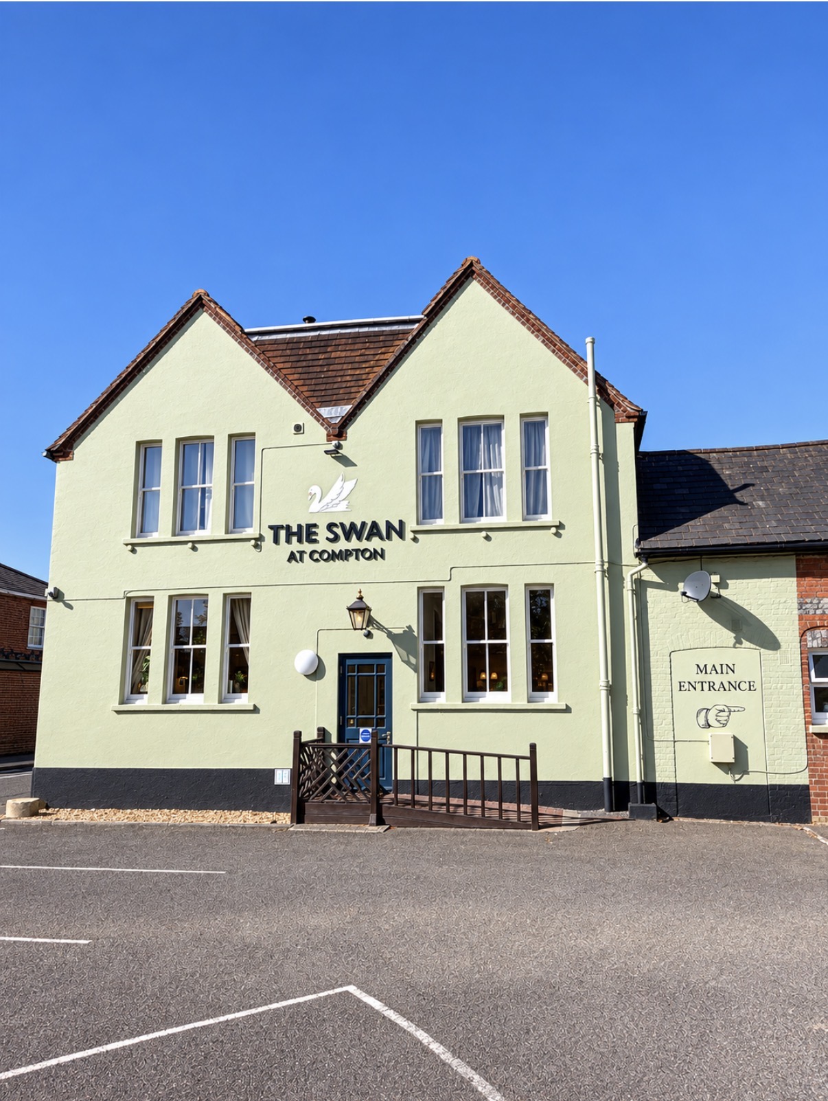 Exterior of The Swan at Compton village pub beneath a clear sky